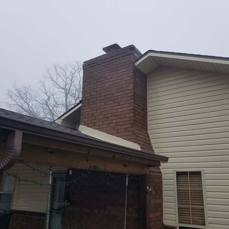 brick home with white siding before pressure wash