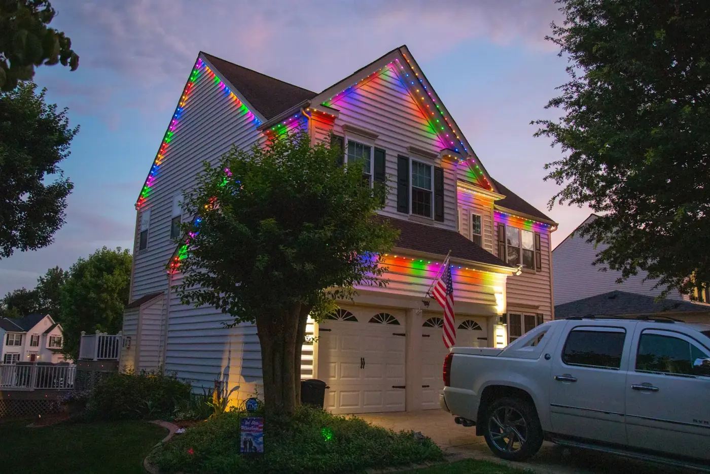Two-story home with full-color permanent lights along every roofline at dusk